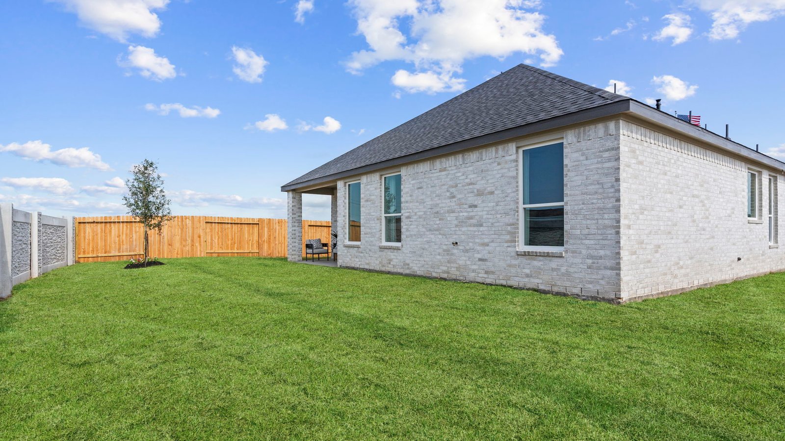 Outdoor covered patio with seating area overlooking a well-maintained lawn, perfect for relaxation.