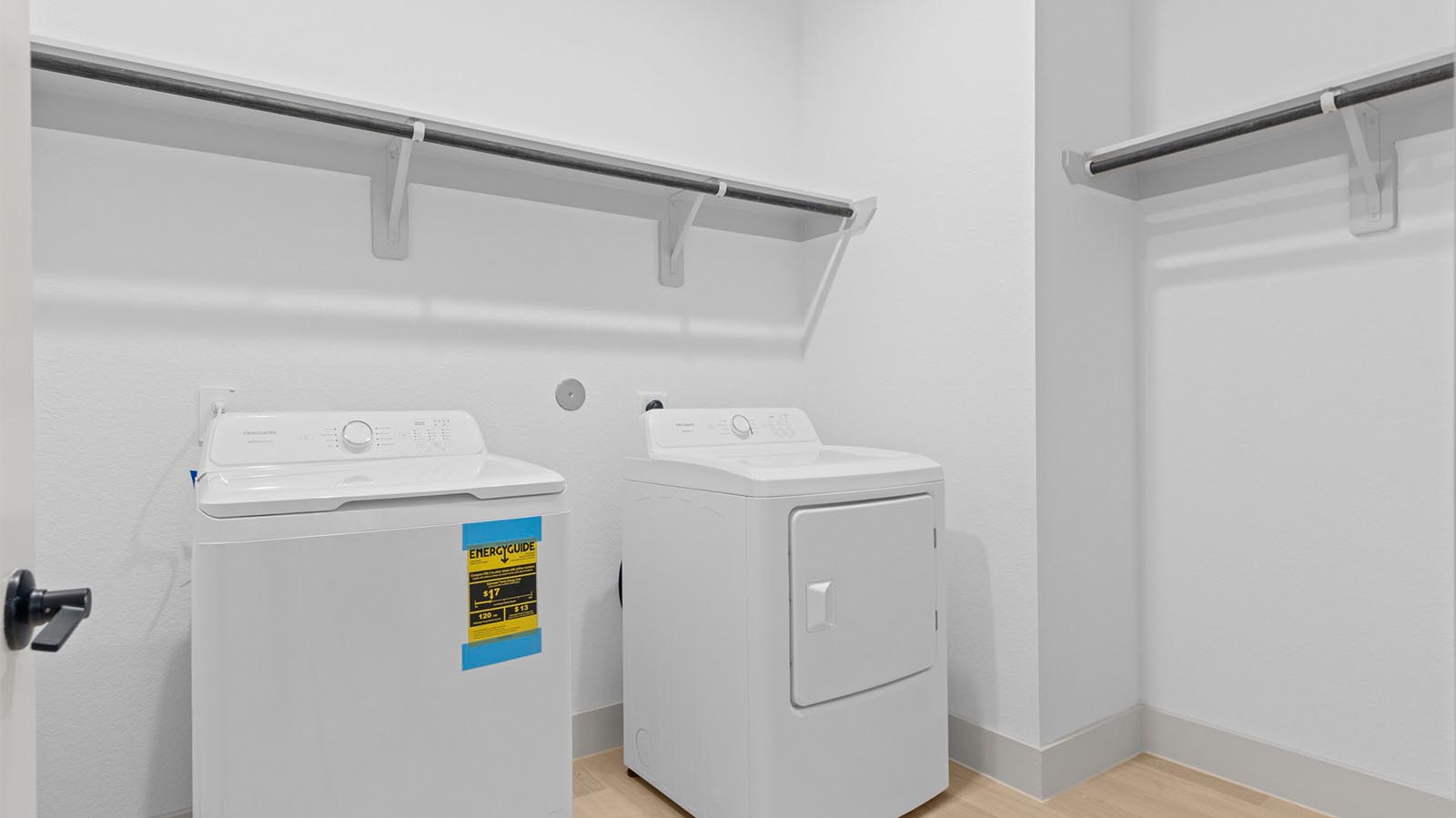 A laundry room featuring a washer and dryer, neatly arranged with ample space for laundry tasks and storage.