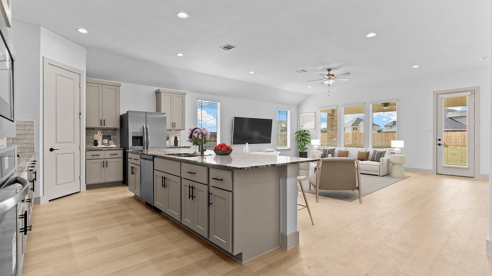 Bright and spacious kitchen with quartz countertops, stainless steel appliances, and an island with bar seating.