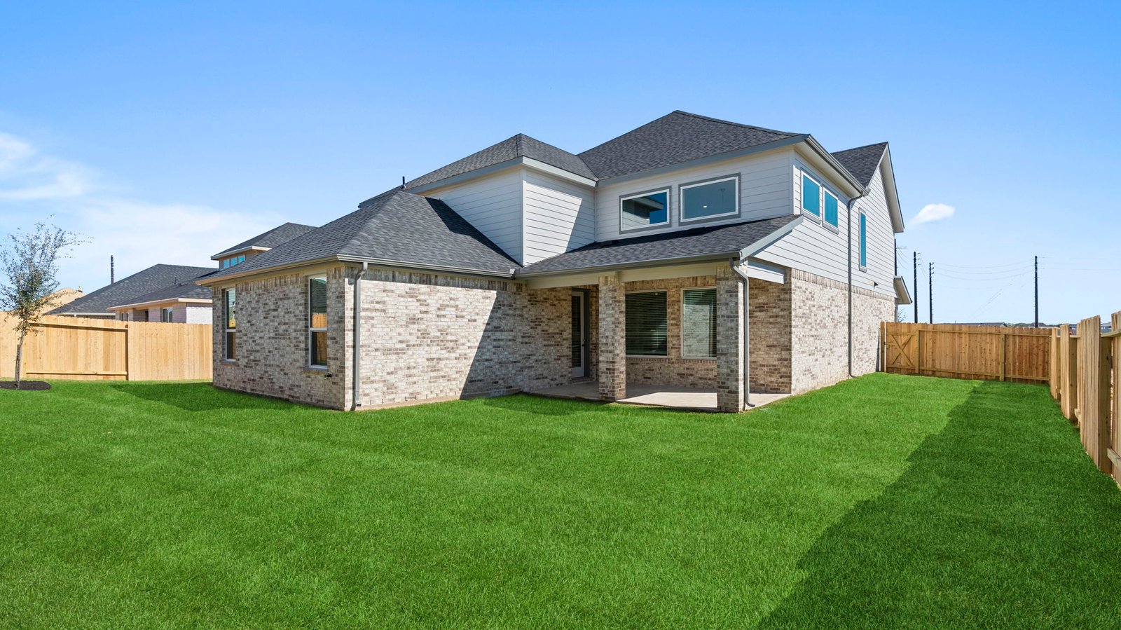 Outdoor covered patio with seating area overlooking a well-maintained lawn, perfect for relaxation.