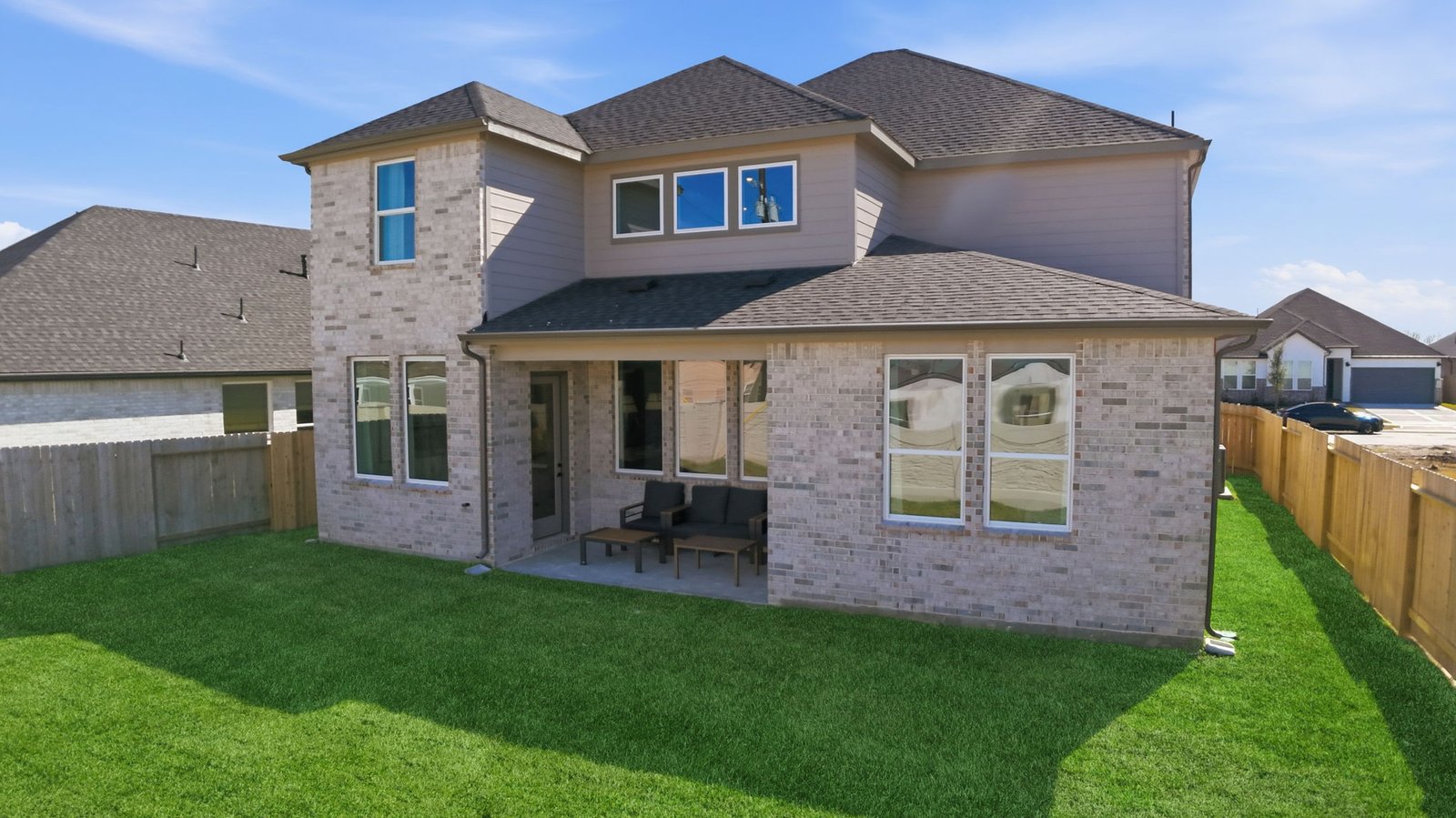 Outdoor covered patio with seating area overlooking a well-maintained lawn, perfect for relaxation.