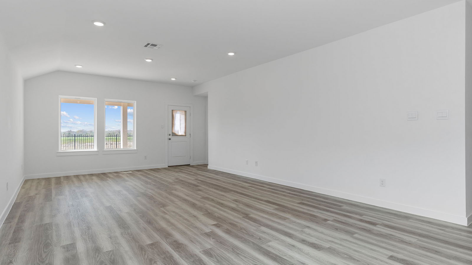Spacious living room with two large windows and back patio door
