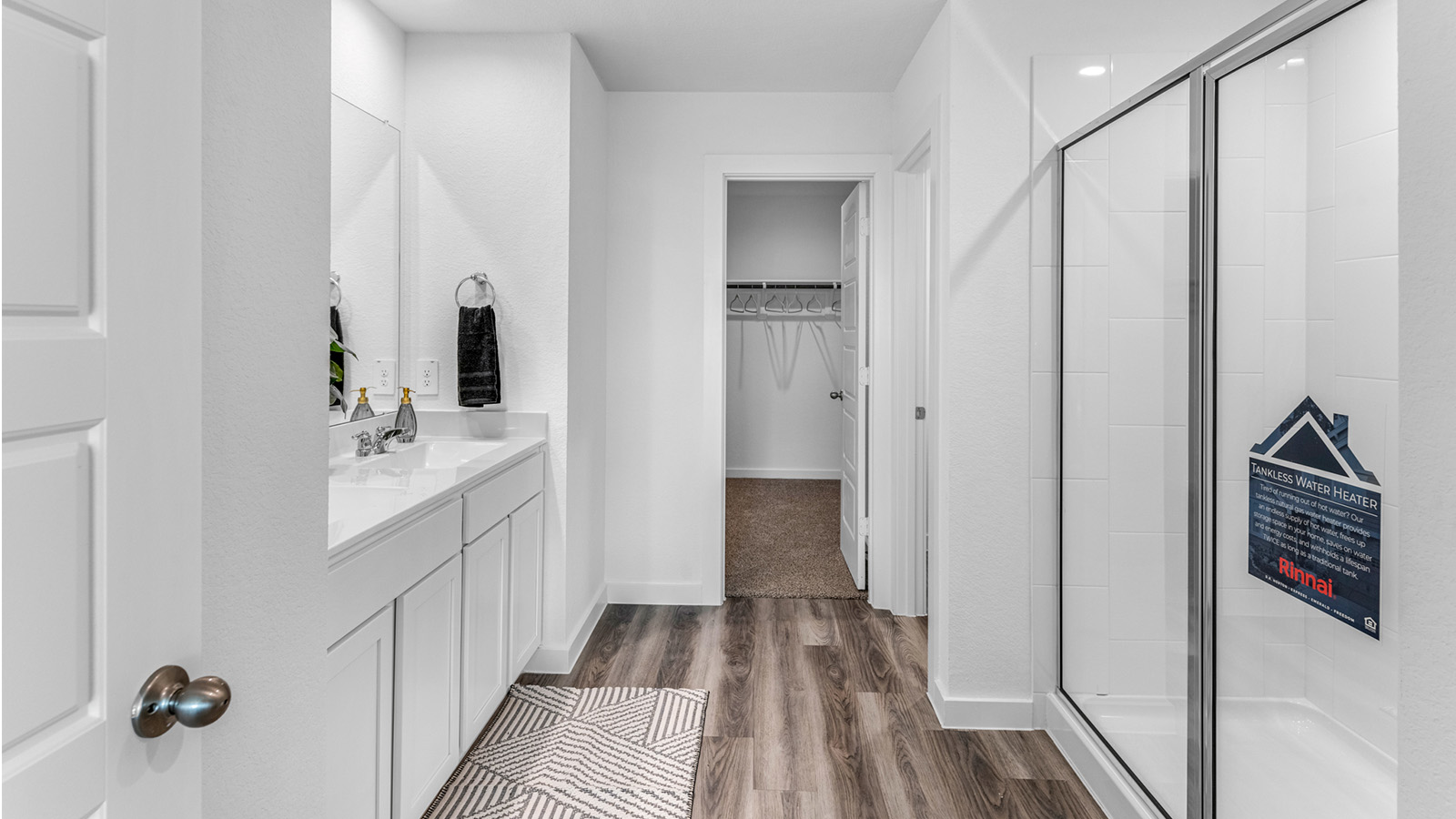 Modern primary bathroom with double vanities, quartz countertops, and a glass-enclosed shower with a walk-in closet.