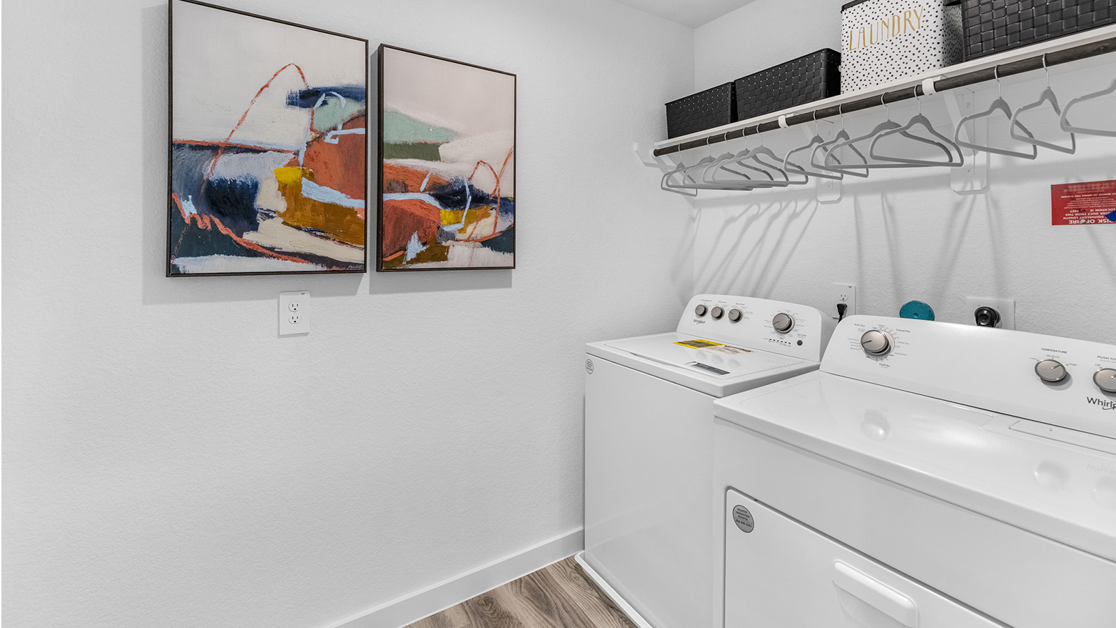 A laundry room featuring a washer and dryer, neatly arranged with ample space for laundry tasks and storage.