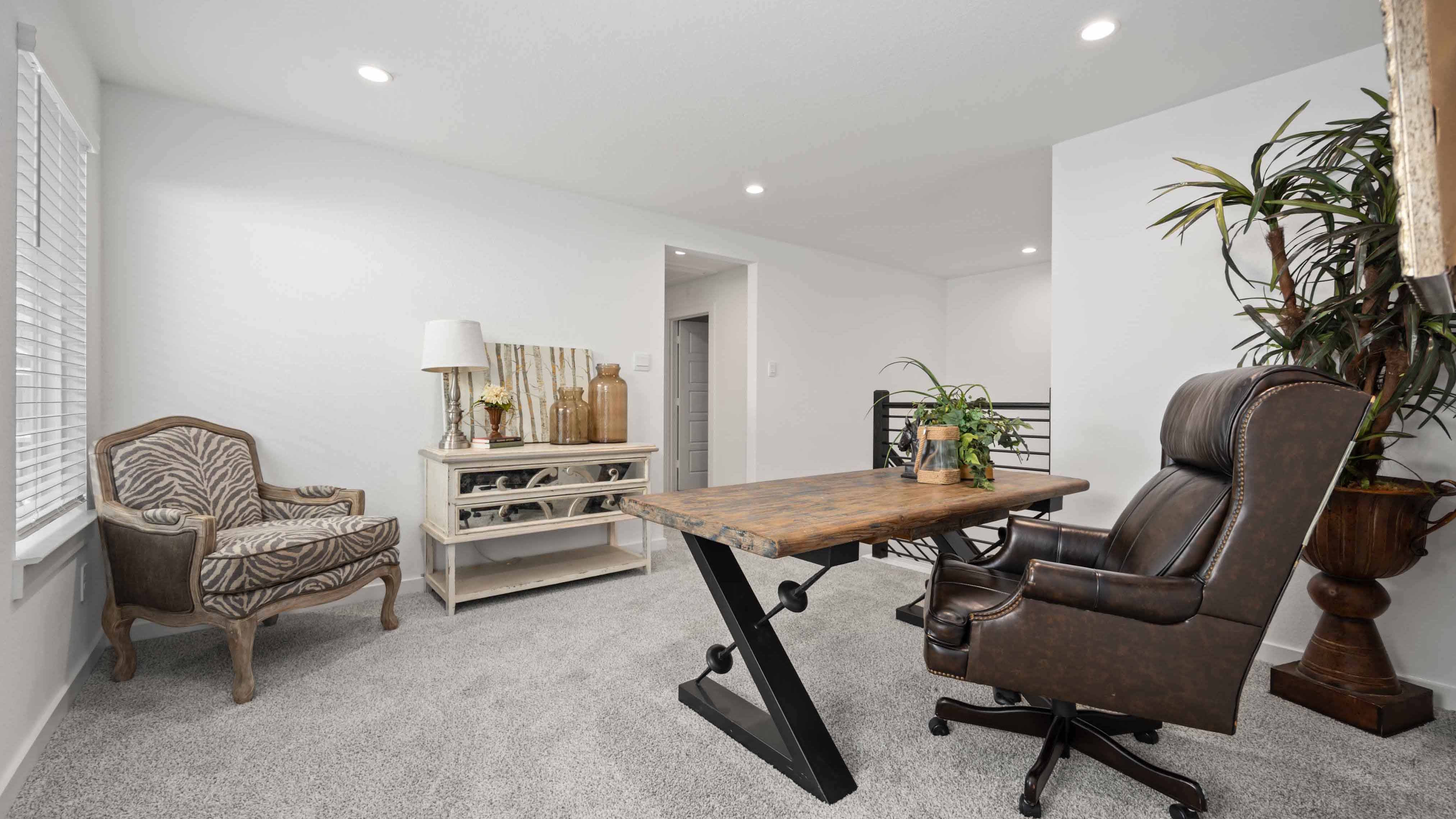 A spacious upstairs game room with plenty of natural light from windows overlooking side of the home