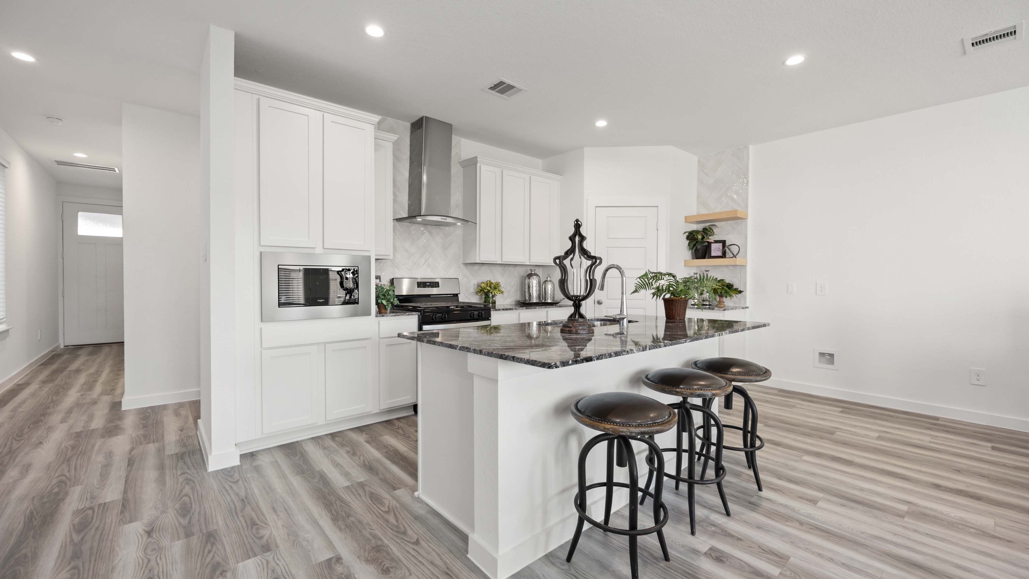 An open concept kitchen with an island with bar seating and access to the living and dining areas.