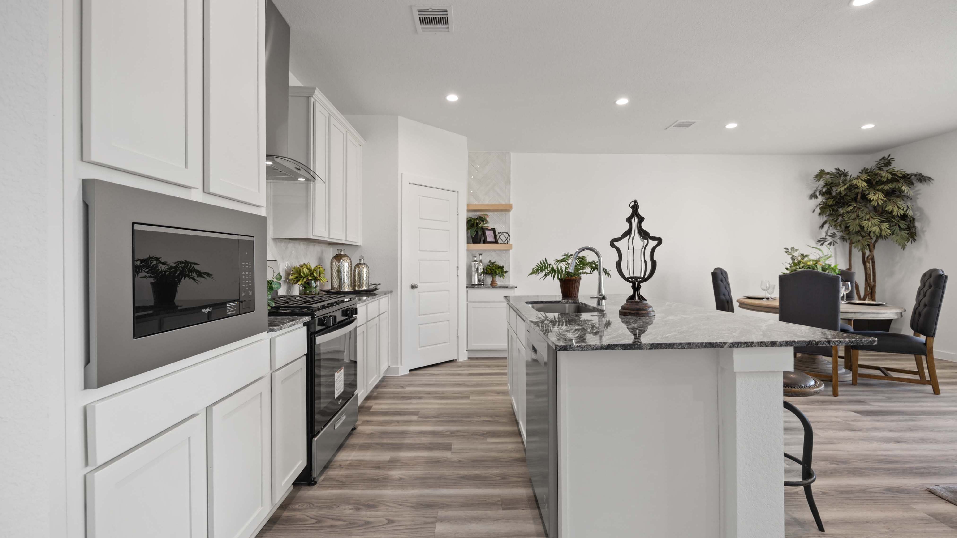 An open concept kitchen with an island with bar seating and access to the living and dining areas.