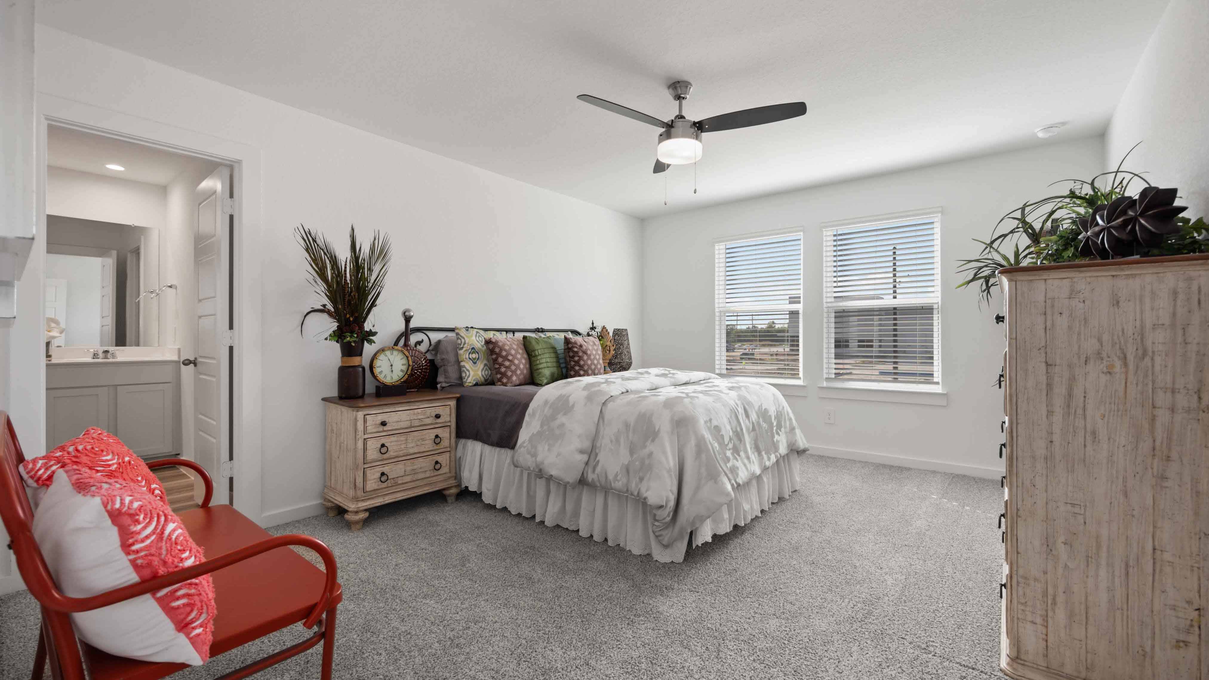 A spacious primary bedroom emphasizing open space and natural lighting with large windows.