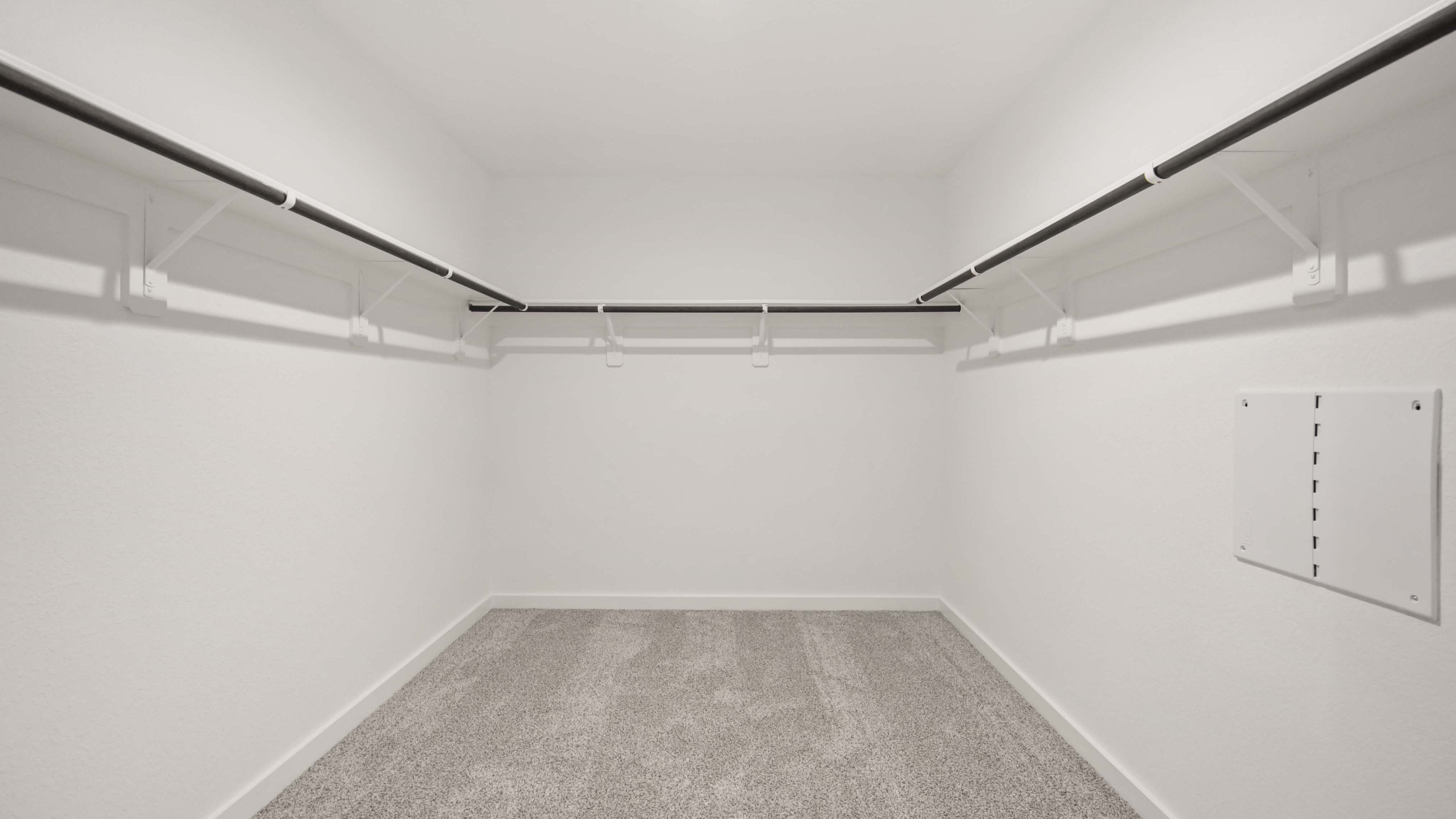 A spacious walk-in closet off the primary bathroom with multiple hanging rods, and shelves for maximum storage capabilities.