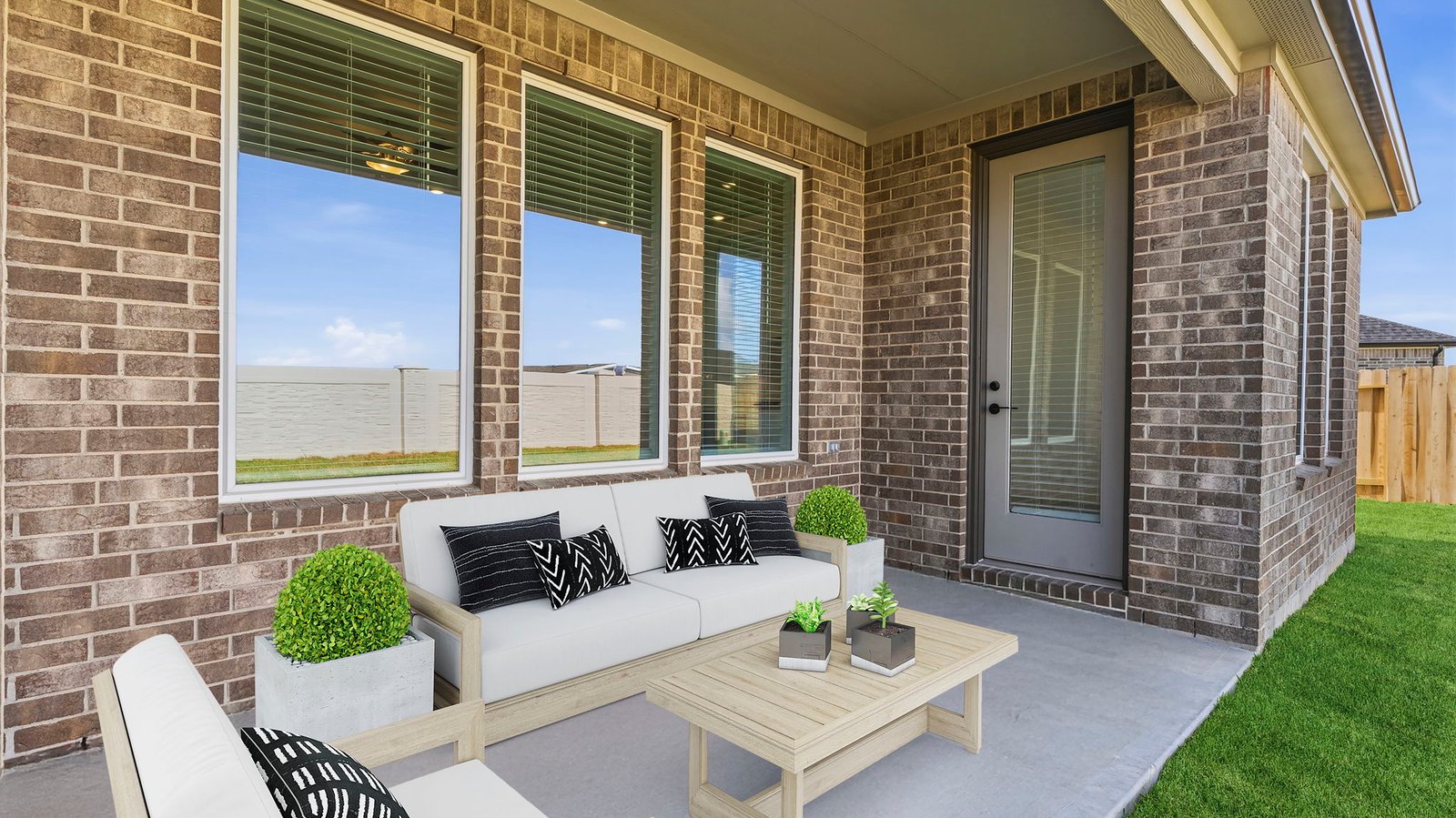 Outdoor covered patio with seating area overlooking a well-maintained lawn, perfect for relaxation.