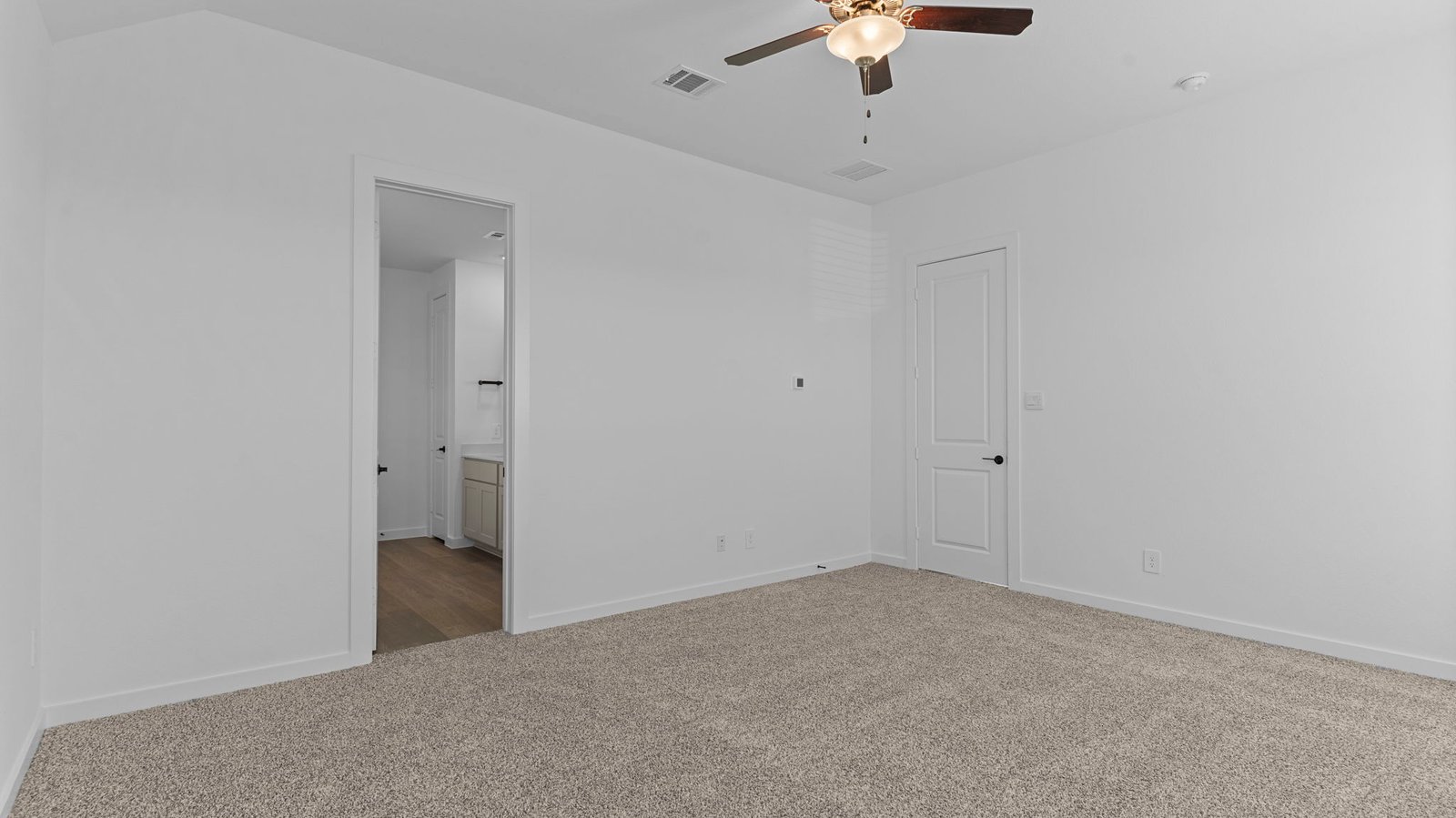 A spacious primary bedroom emphasizing open space and natural lighting with large windows.