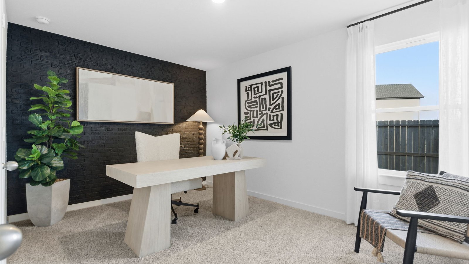 A bedroom shown as an at home office with a bright window allowing natural light to enter.
