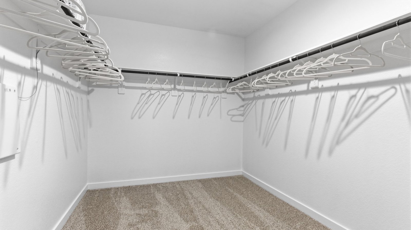 A spacious walk-in closet off the primary bathroom with multiple hanging rods, and shelves for maximum storage capabilities.