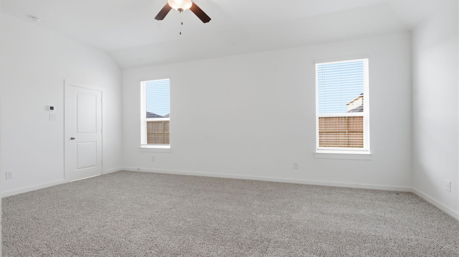 Primary bedroom with ceiling fan, plush carpeting, and a large walk-in closet.