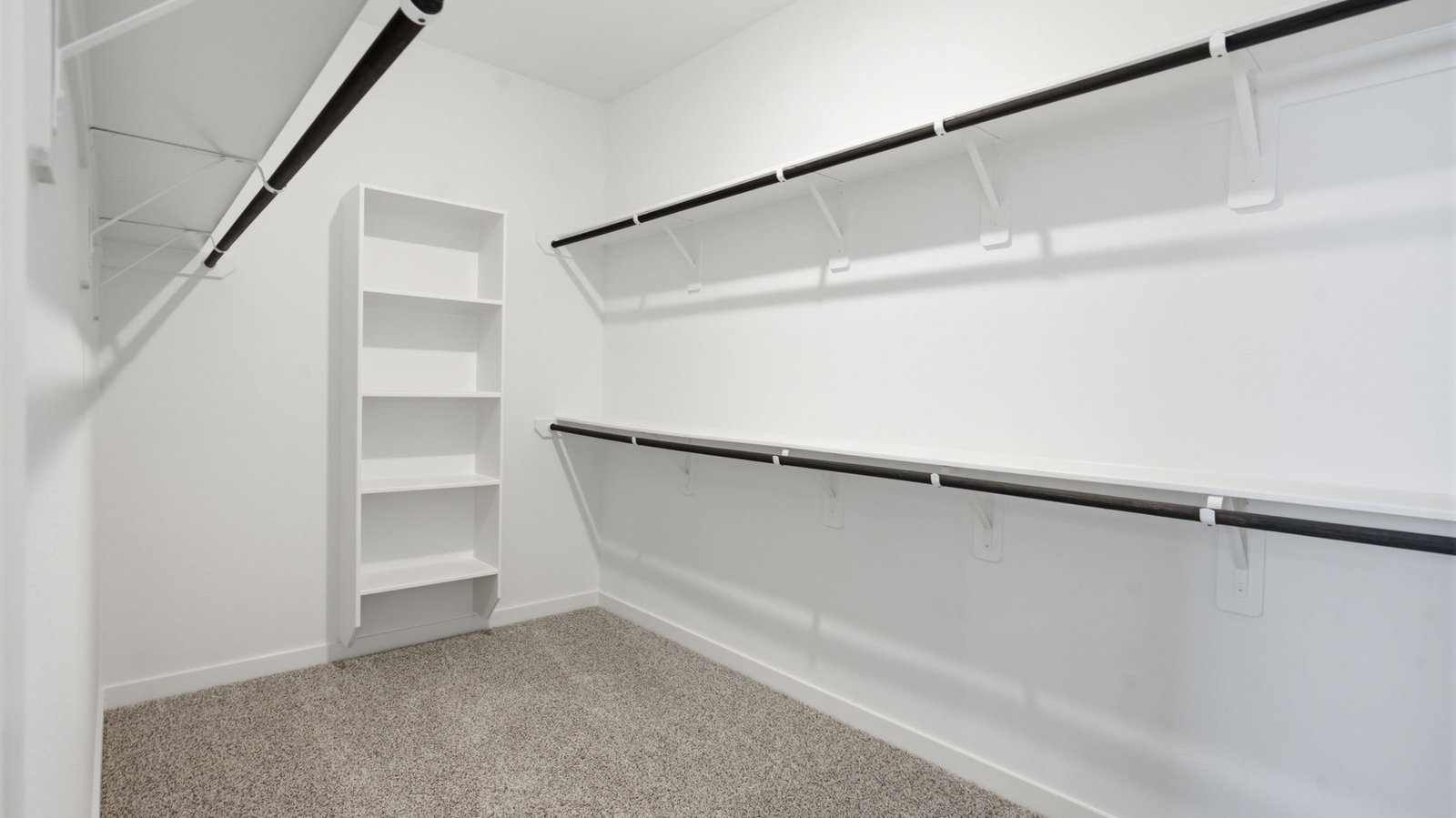 A spacious walk-in closet off the primary bathroom with multiple hanging rods, and shelves for maximum storage capabilities.