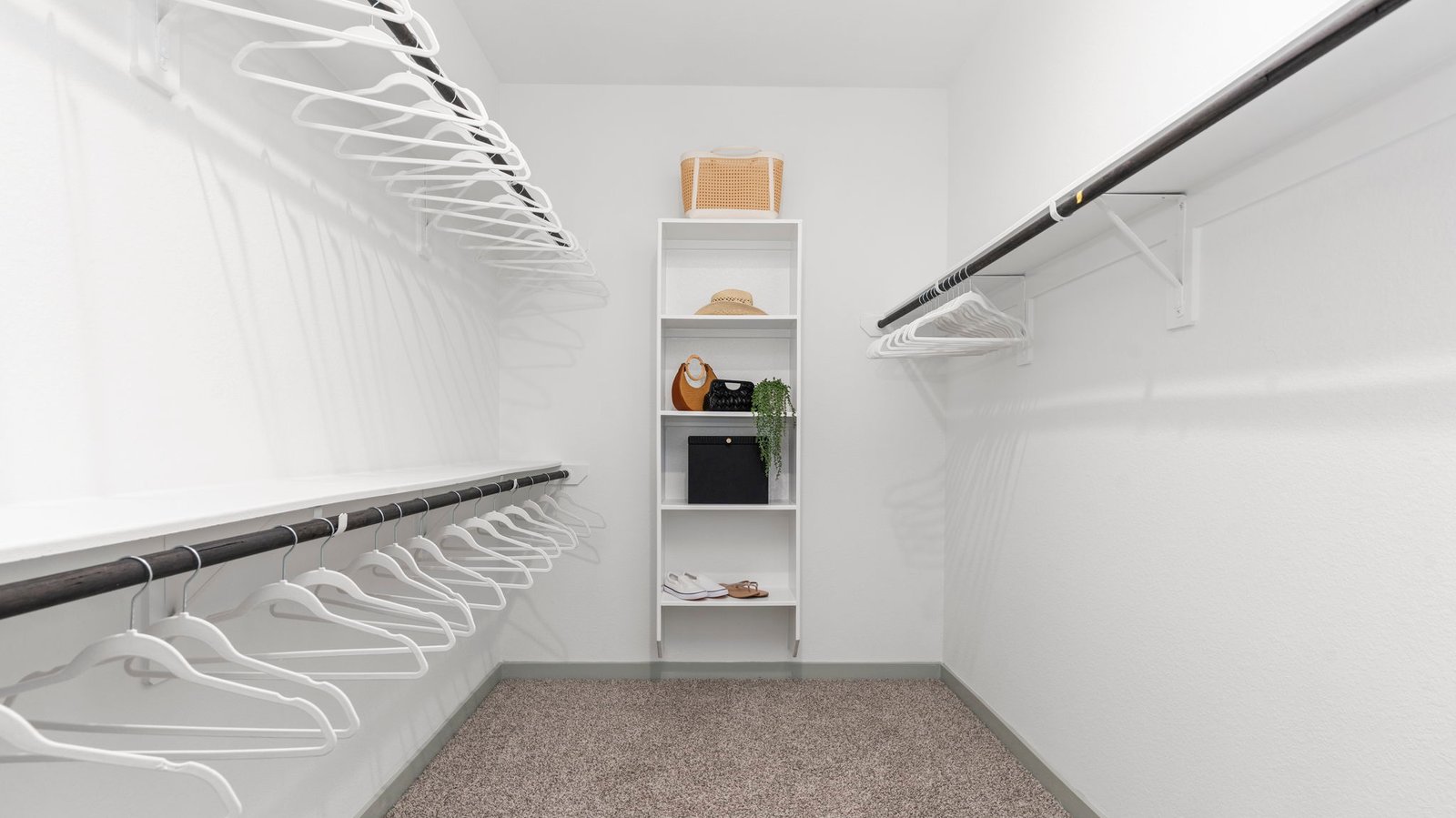 A spacious walk-in closet off the primary bathroom with multiple hanging rods, and shelves for maximum storage capabilities.