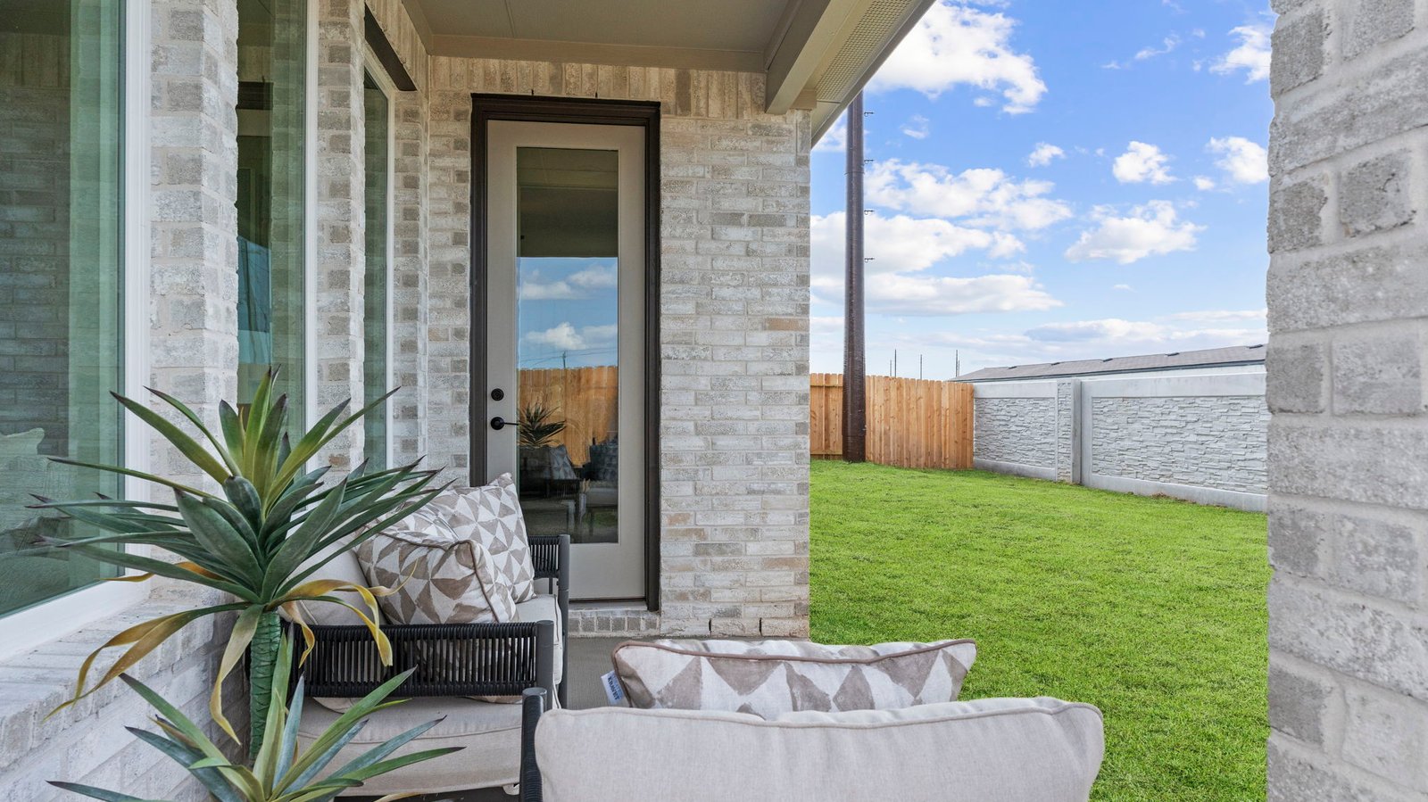 Outdoor covered patio with seating area overlooking a well-maintained lawn, perfect for relaxation.