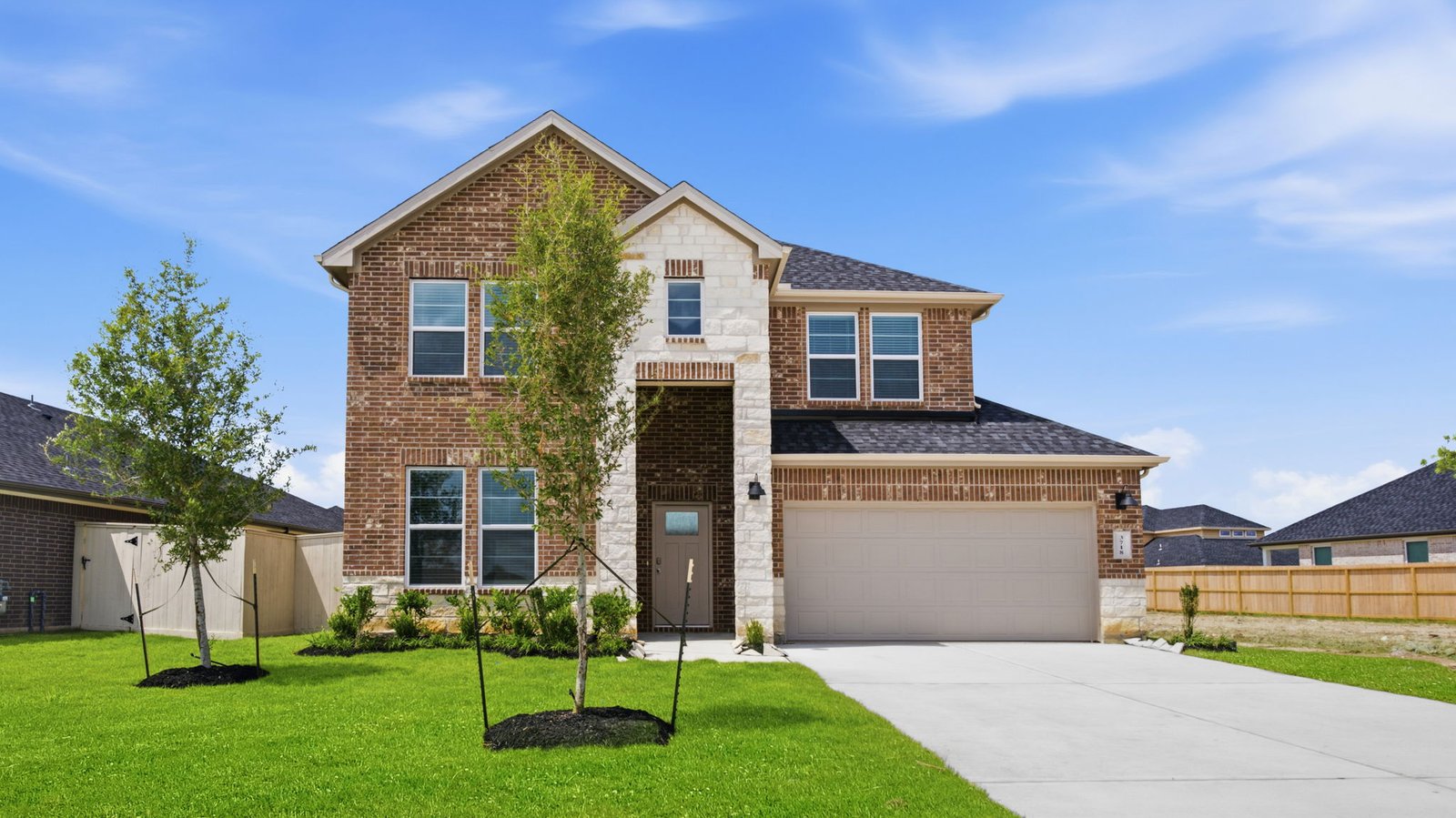 A two-story home with brick and stone exterior with a two-car garage and a well-maintained front lawn in league city
