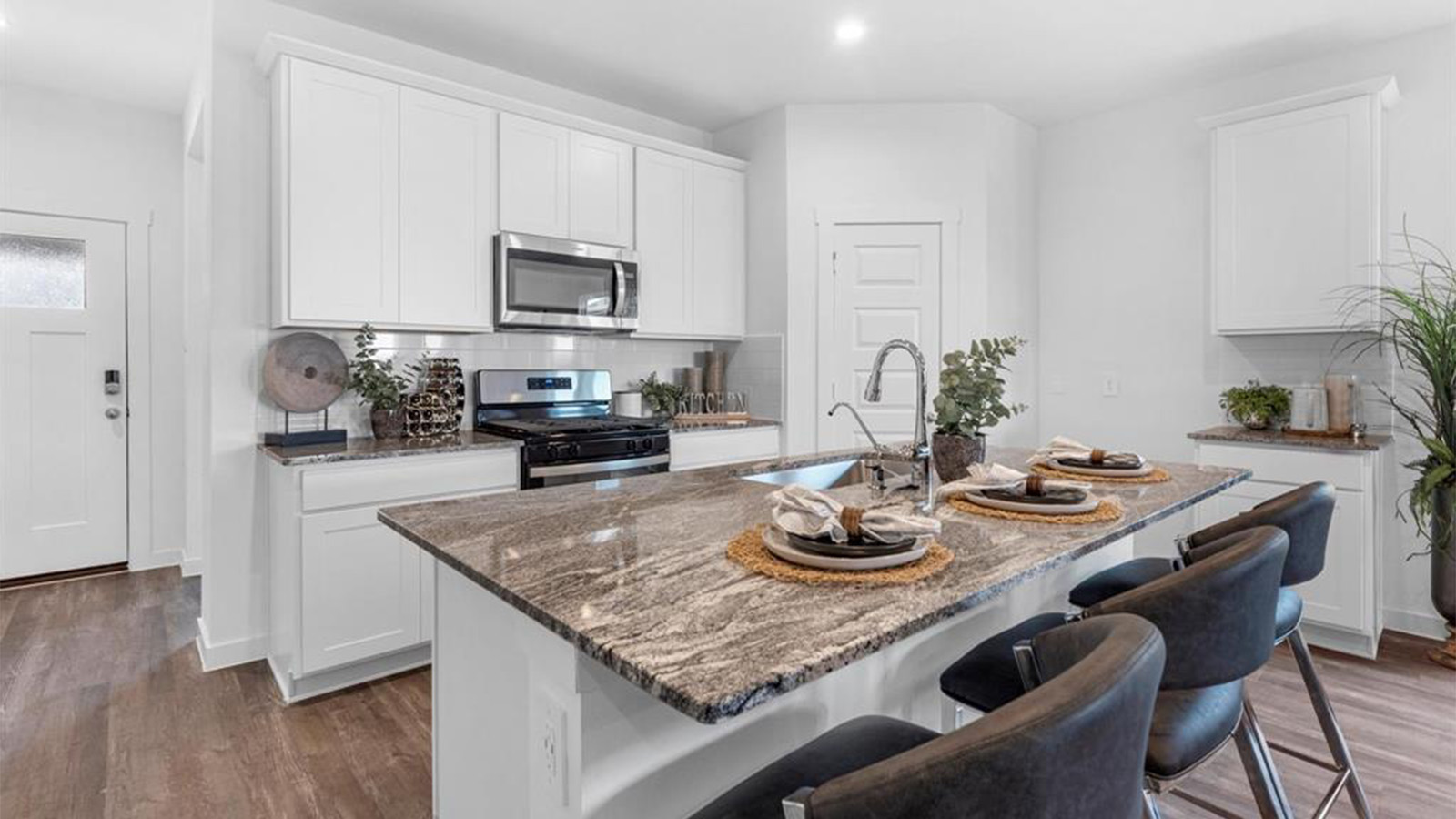 Bright and spacious kitchen with granite countertops, stainless steel appliances, and an island with bar seating.