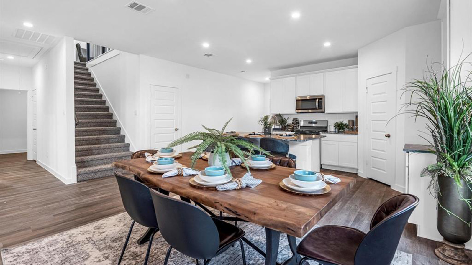 Spacious dining area with vinyl wood flooring, large window and tall ceiling.