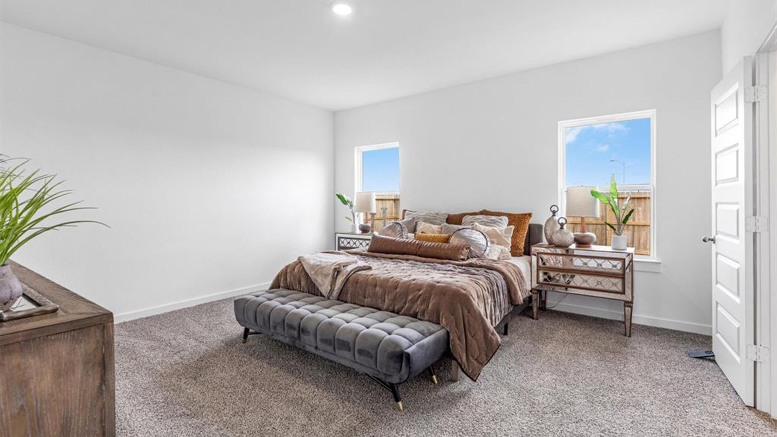 Primary bedroom with ceiling fan, plush carpeting, and a large walk-in closet.