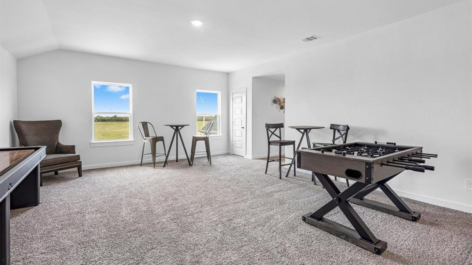 A spacious upstairs living area with plenty of natural light from windows overlooking side of the home