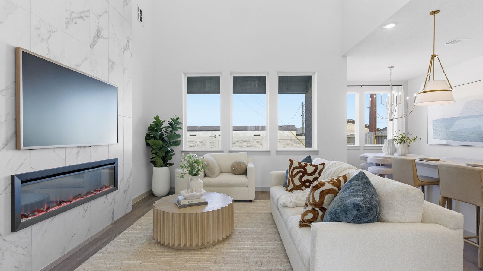A luxurious living room featuring tall ceilings, large windows for natural lighting wood flooring and a view to the backyard.