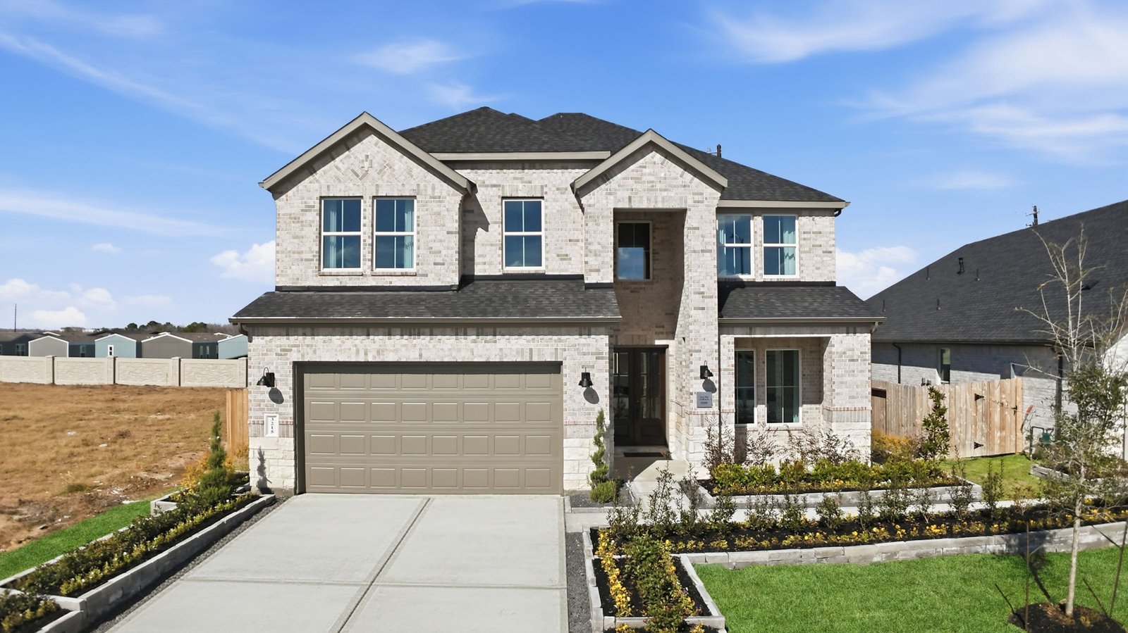 A two-story home with brick and stone exterior with a two-car garage and a well-maintained front lawn in league city