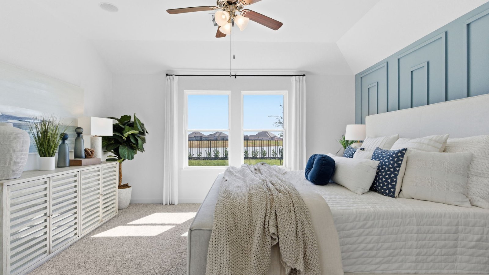 Primary bedroom with ceiling fan, plush carpeting, and a large walk-in closet.