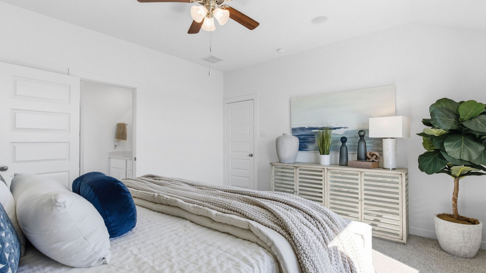 Primary bedroom with ceiling fan, plush carpeting, and a large walk-in closet.