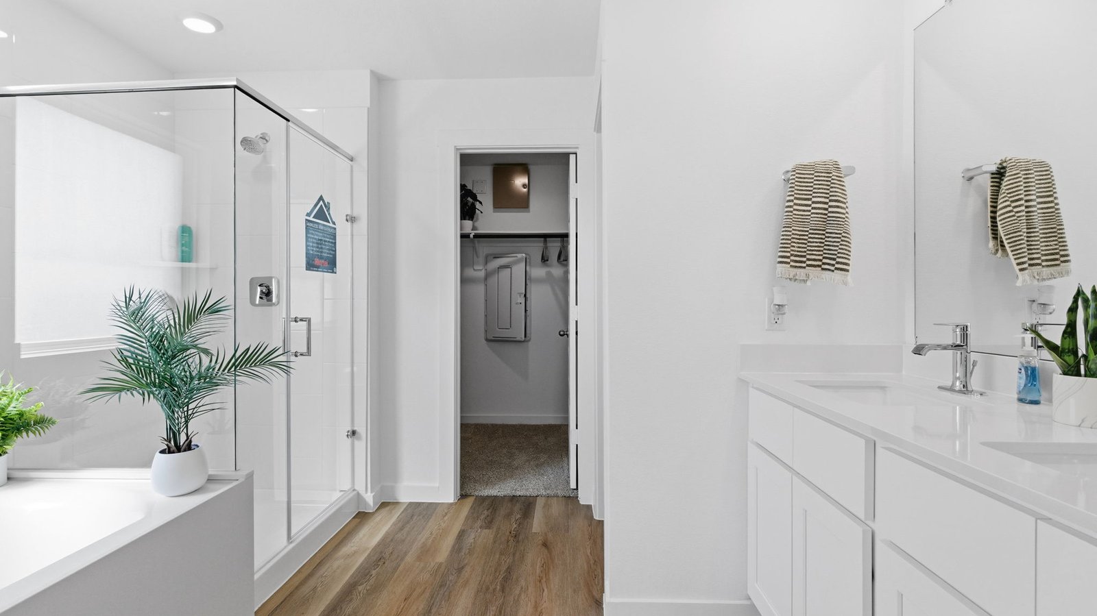 Modern primary bathroom with double vanities, granite countertops, and a glass-enclosed shower with a walk-in closet.