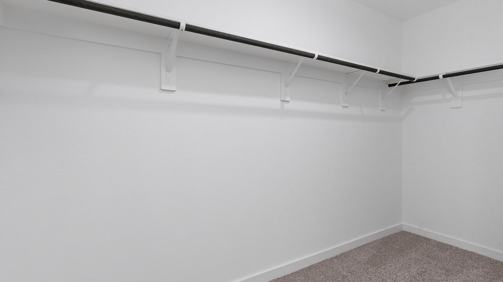 A spacious walk-in closet off the primary bathroom with multiple hanging rods, and shelves for maximum storage capabilities.