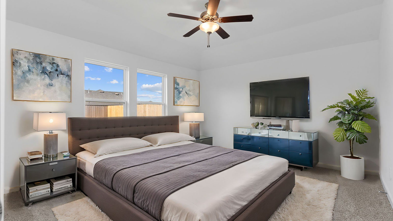 Primary bedroom with ceiling fan, plush carpeting, and a large walk-in closet.