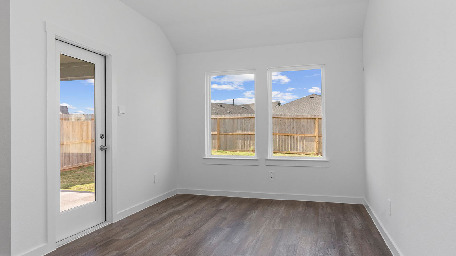 Formal dining room with large windows, wood floors, and view of the backyard.