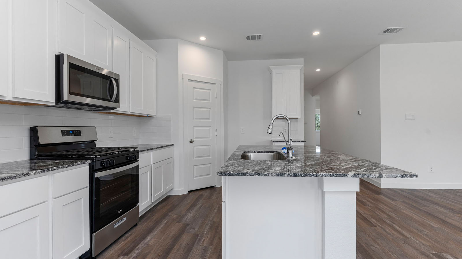 Bright and spacious kitchen with granite countertops, stainless steel appliances, and an island with bar seating.