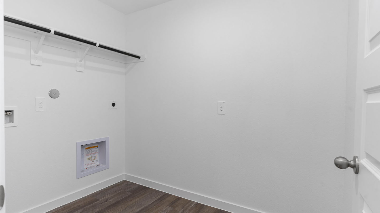 Spacious laundry room with washer and dryer connections, hanging rod, and vinyl wood flooring