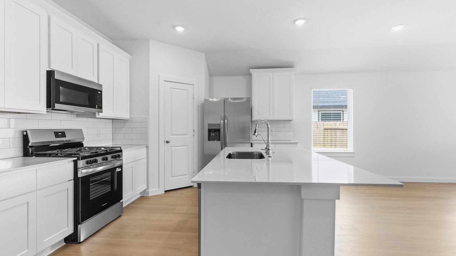 Bright and spacious kitchen with quartz countertops, stainless steel appliances, and an island with bar seating.