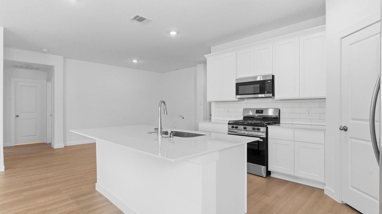 An open concept kitchen with an island with bar seating and access to the living and dining areas.