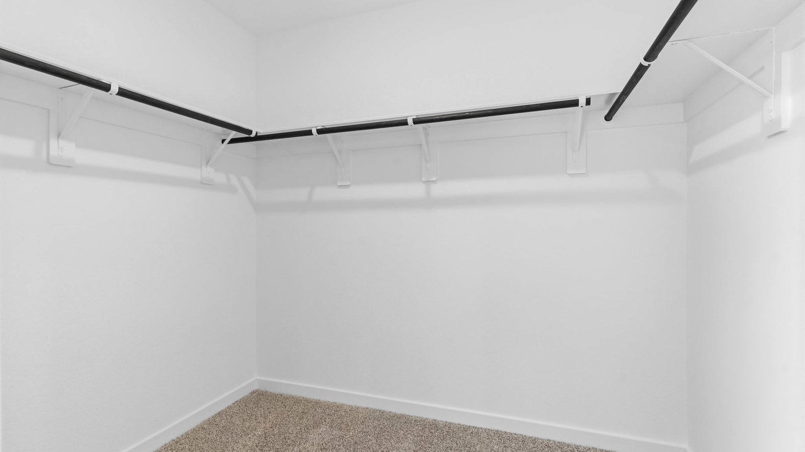 A spacious walk-in closet off the primary bathroom with multiple hanging rods, and shelves for maximum storage capabilities.