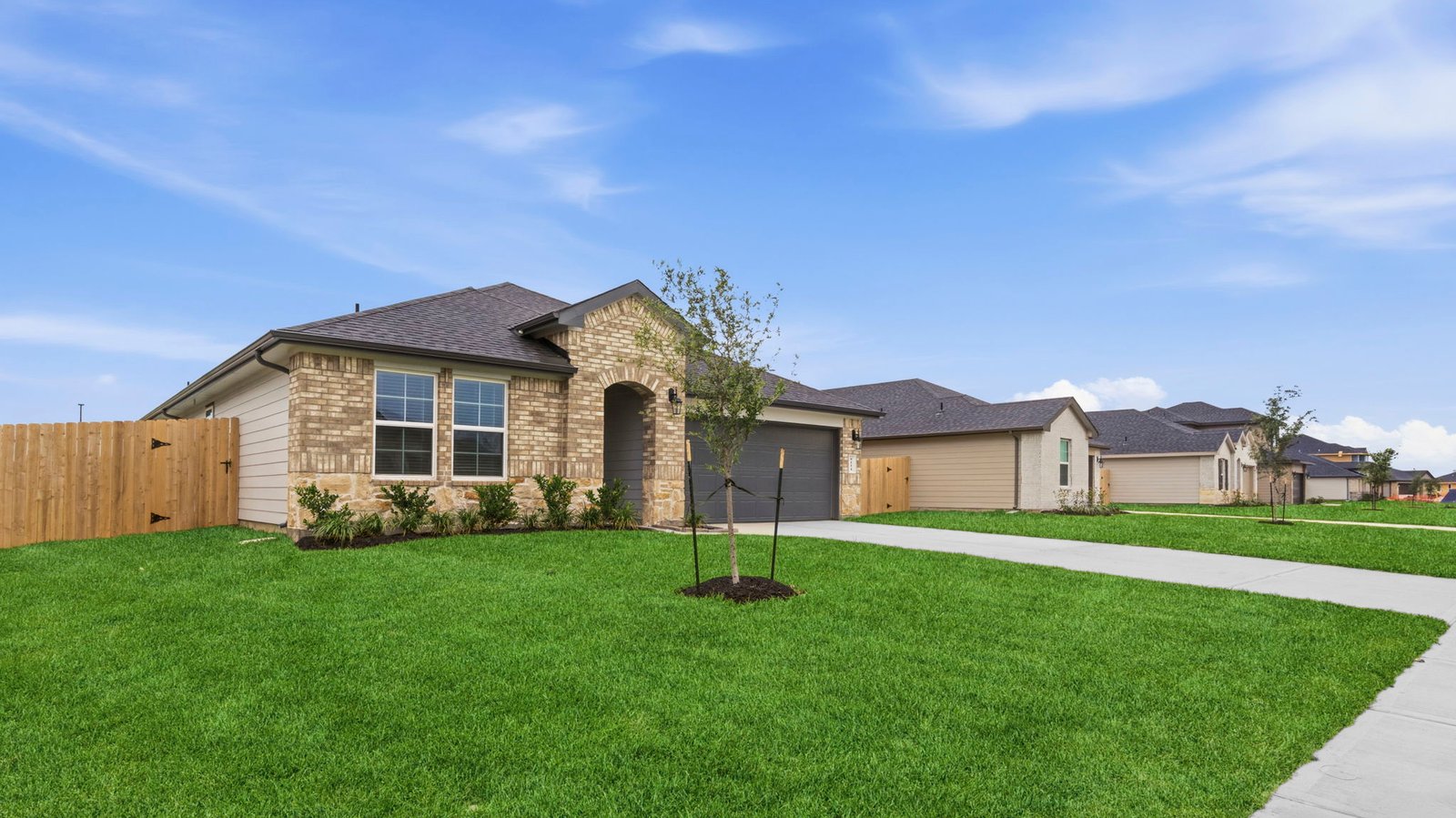 An side view of the newly built one story home with traditional architecture, a two car garage and a landscaped front yard