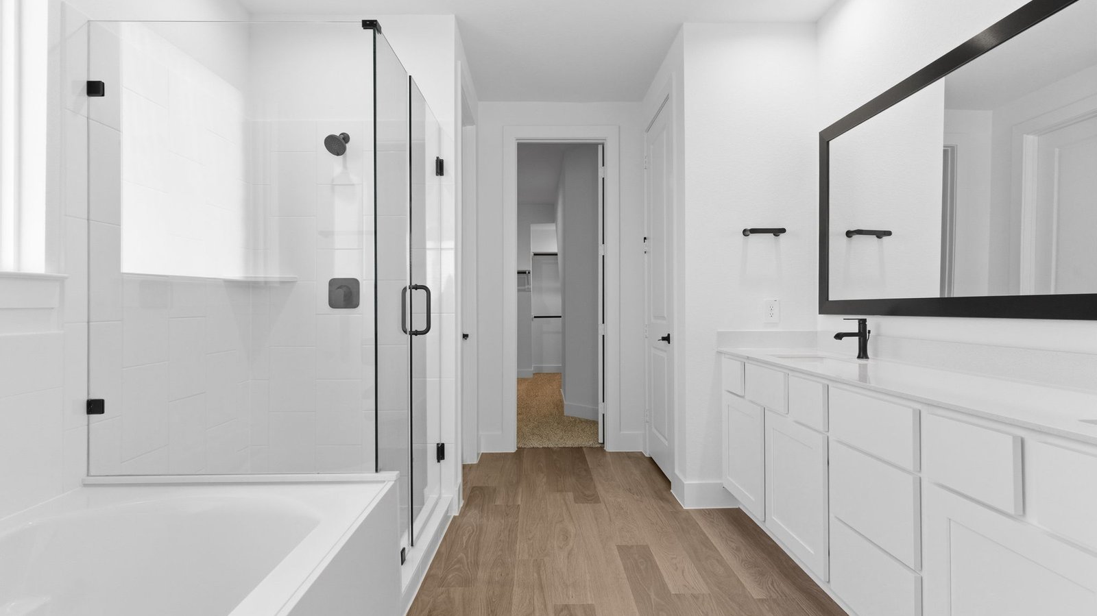 Luxurious primary bathroom with dual vanities, a soaking tub, glass-enclosed shower and walk-in closet.