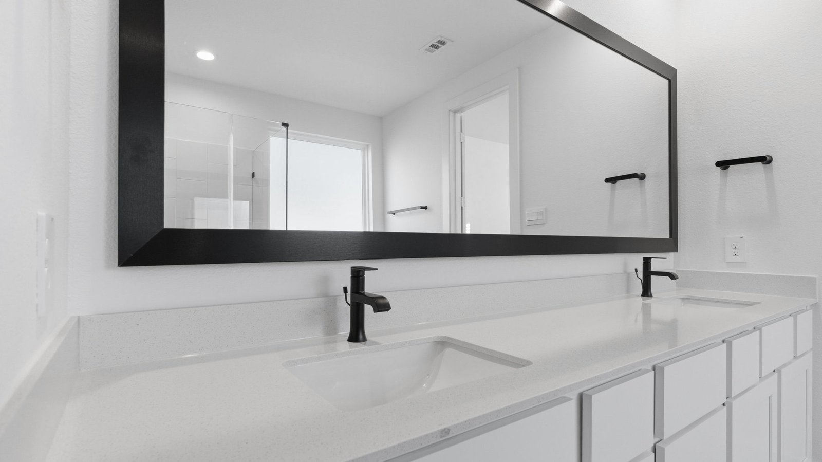 Modern primary bathroom with double vanities, quartz countertops,