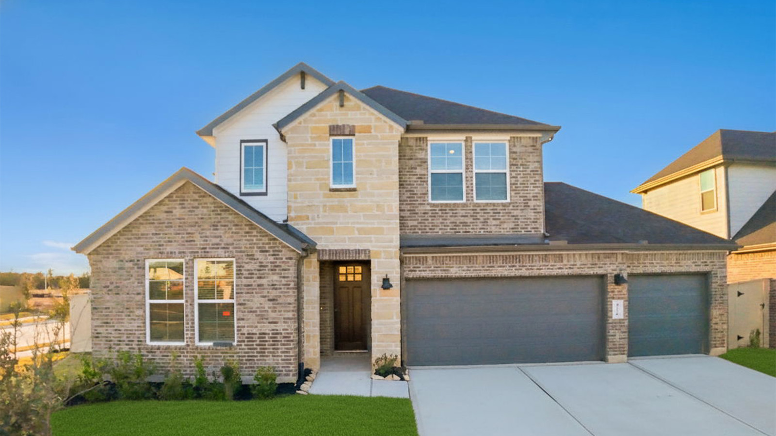Newly built two story home with traditional architecture, a double garage, and landscaped front yard.