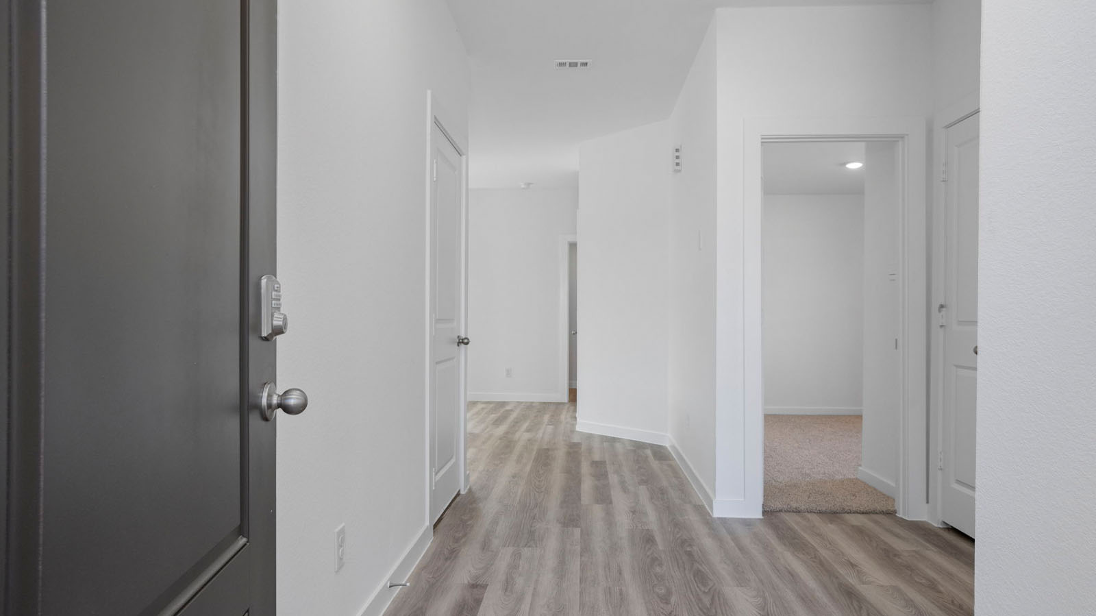 Entryway into home leading to a hallway with bedrooms