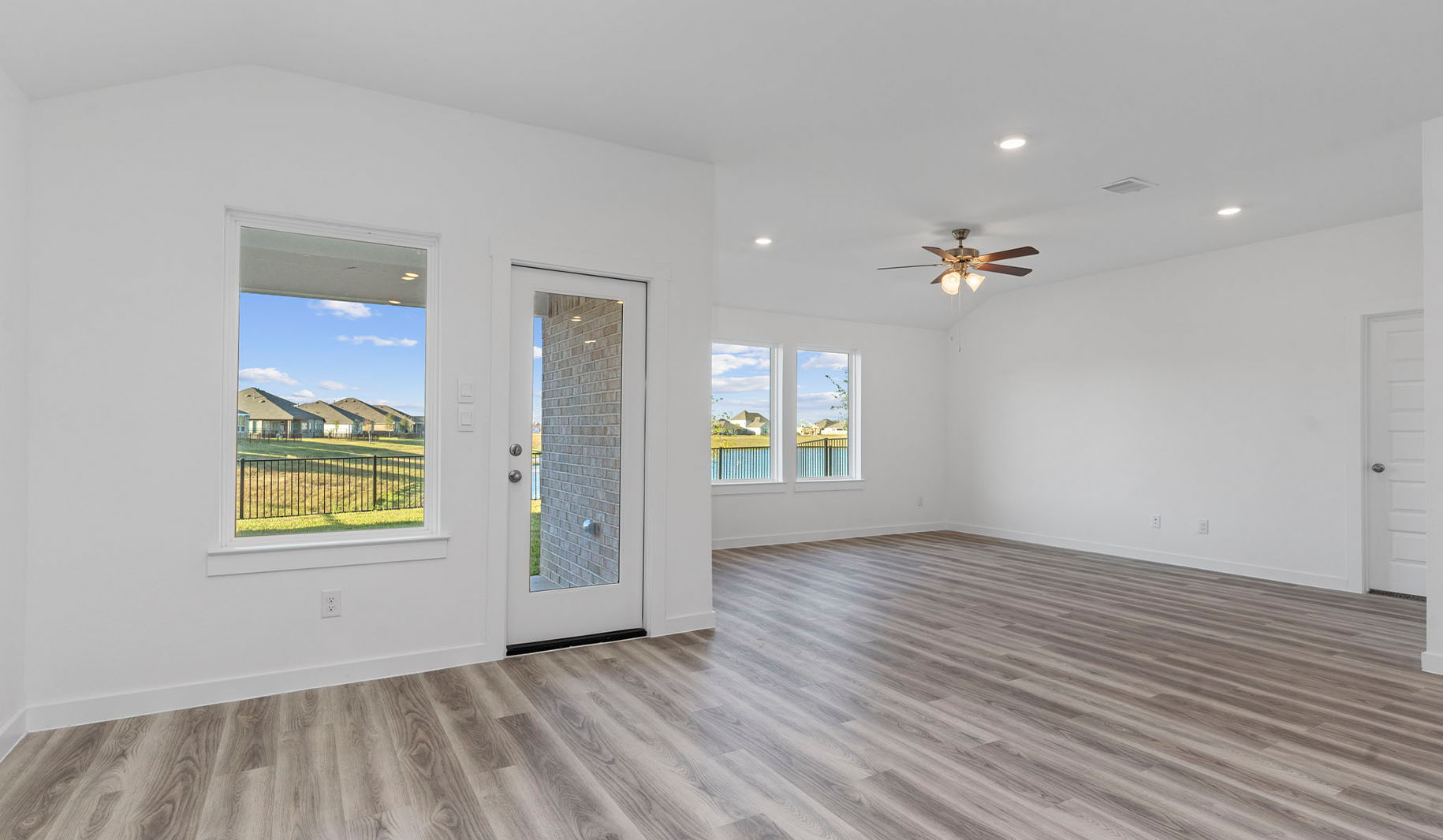 Open concept dining room and living room with three large windows and back patio door