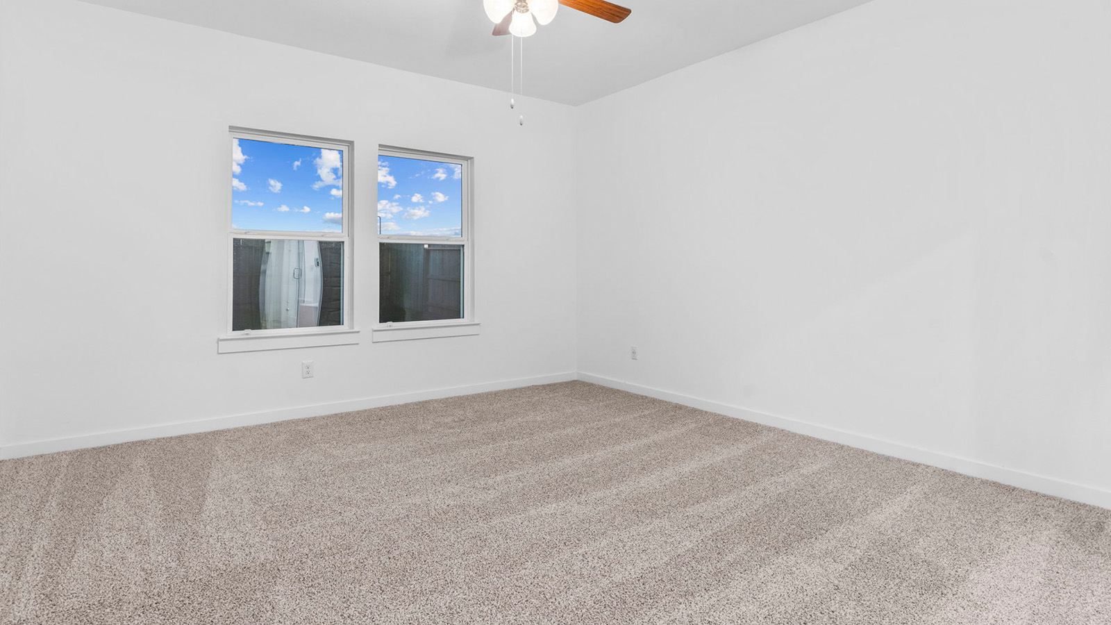 Primary bedroom with a celling fan and two large windows