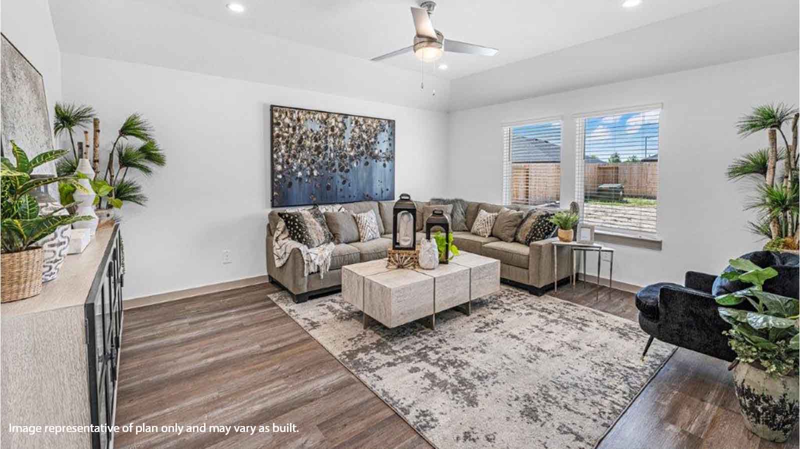 Spacious living room with brown flooring, white walls and windows