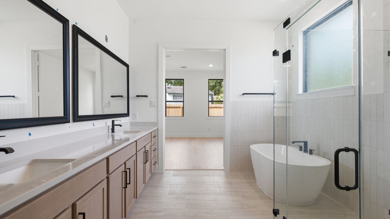 Luxurious primary bathroom with dual vanities, a soaking tub, and separate glass-enclosed walk in shower