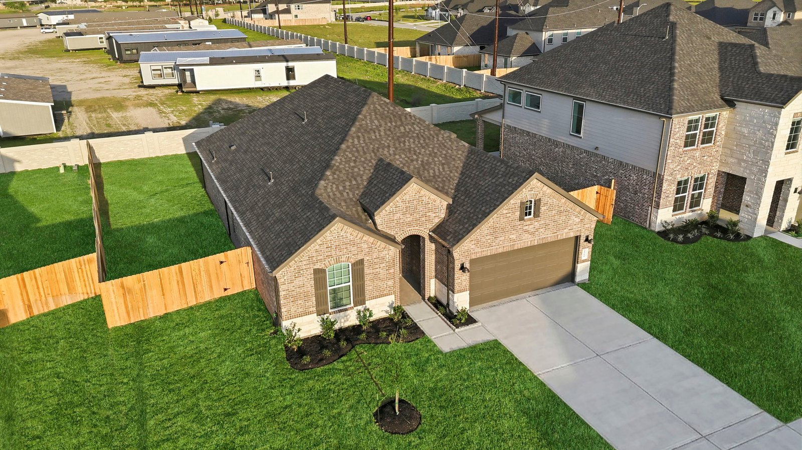 An aerial view of the newly built one story home with traditional architecture, a two car garage and a landscaped front yard