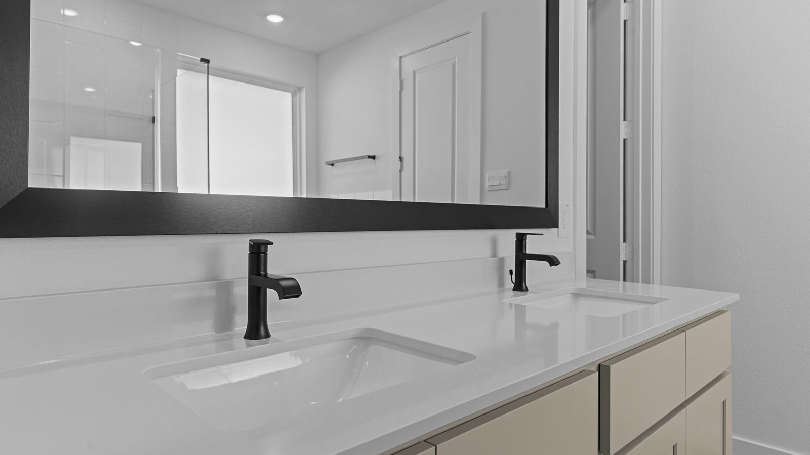 Modern primary bathroom with double vanities, quartz countertops, and a glass-enclosed shower with a walk-in closet.